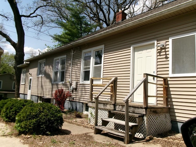 view of side of home with a chimney and central AC unit
