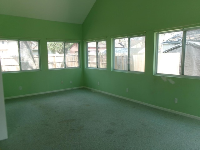 carpeted empty room with baseboards, vaulted ceiling, and a healthy amount of sunlight