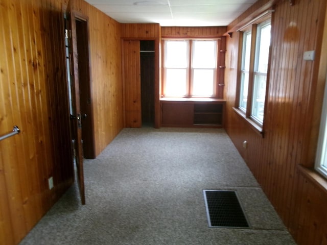 empty room featuring wooden walls, carpet, and visible vents