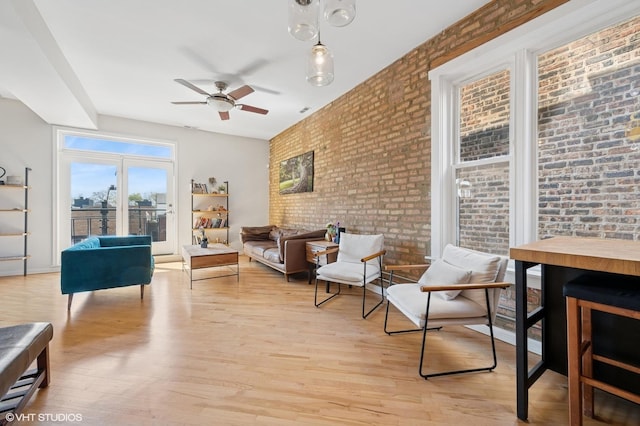 sitting room with brick wall, ceiling fan, and light wood finished floors