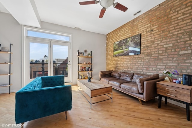 living area featuring brick wall, visible vents, ceiling fan, and light wood-style flooring