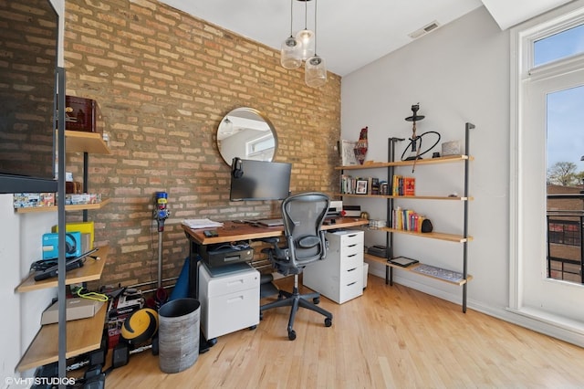 office with wood finished floors, brick wall, and visible vents