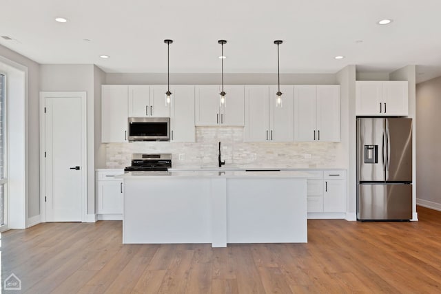 8631 W Grand Ave Unit 4W, River Grove, IL 60171 - kitchen featuring decorative backsplash, a center island, light countertops, white cabinets, and appliances with stainless steel finishes