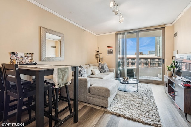 living area with plenty of natural light, ornamental molding, wood finished floors, and visible vents