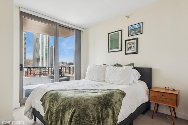 carpeted bedroom with a view of city, baseboards, a wall of windows, and access to exterior