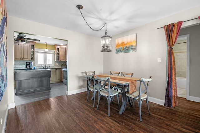 dining space featuring dark wood-style flooring, baseboards, and an inviting chandelier