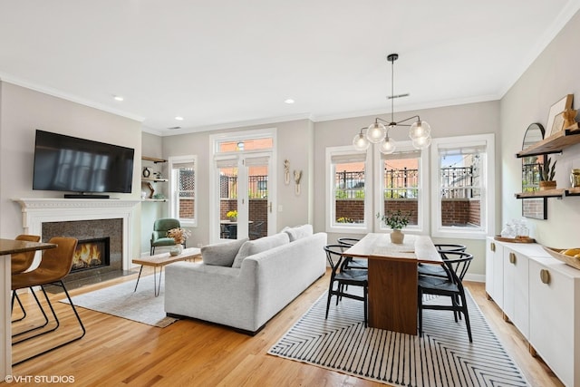 dining space with a fireplace, crown molding, and light wood-style floors
