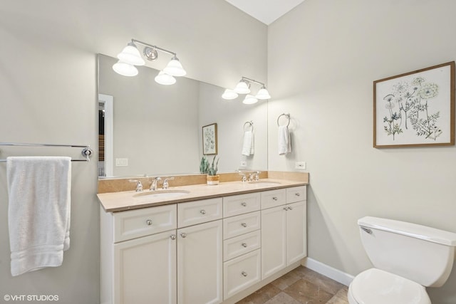full bath with a sink, baseboards, toilet, and double vanity