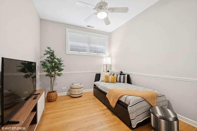 bedroom featuring baseboards, a ceiling fan, wood finished floors, and visible vents