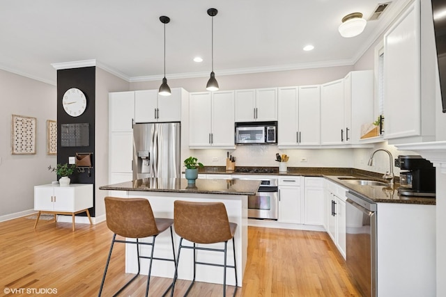 kitchen featuring a sink, a center island, stainless steel appliances, light wood-type flooring, and a kitchen bar