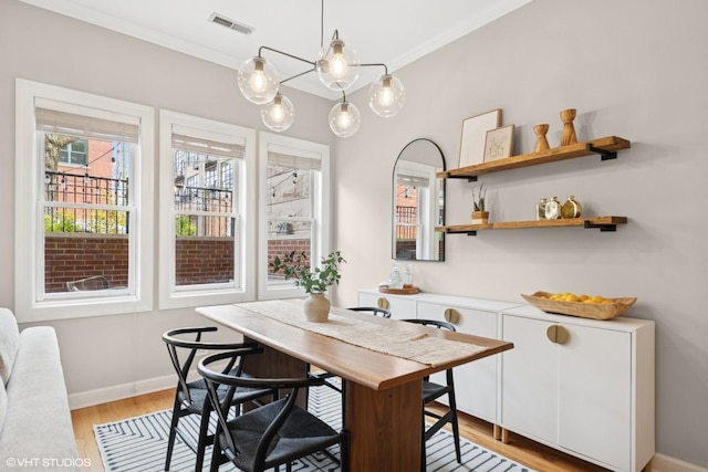 dining area with light wood-type flooring, baseboards, crown molding, and visible vents