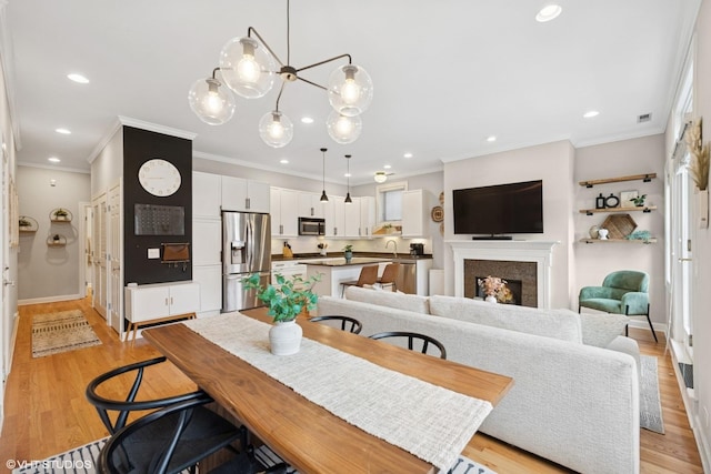 dining space with recessed lighting, visible vents, ornamental molding, and light wood-type flooring