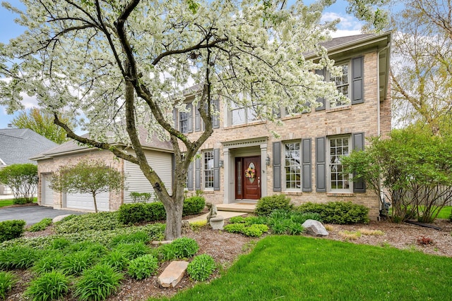 view of front of home with brick siding, an attached garage, and aphalt driveway