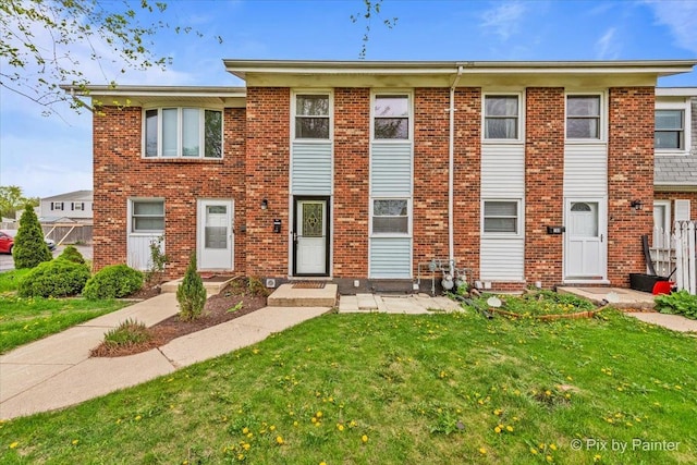 townhome / multi-family property featuring brick siding and a front yard