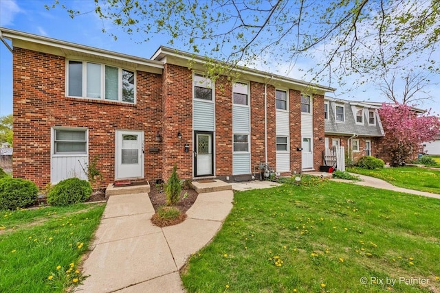 townhome / multi-family property with brick siding and a front lawn
