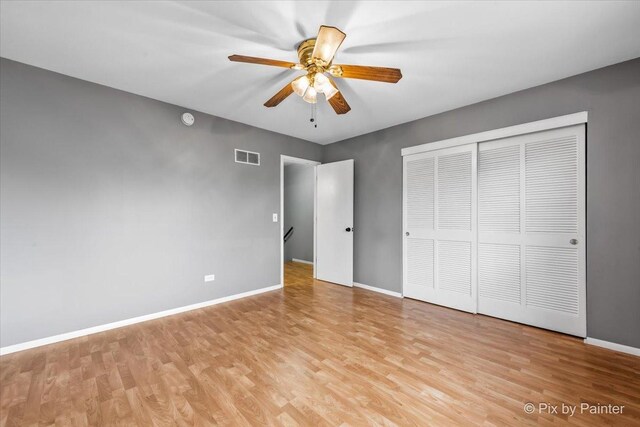 unfurnished bedroom featuring light wood-style floors, baseboards, a closet, and visible vents