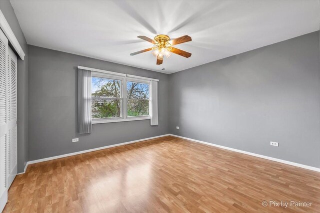 unfurnished bedroom featuring baseboards, ceiling fan, a closet, and light wood-style flooring