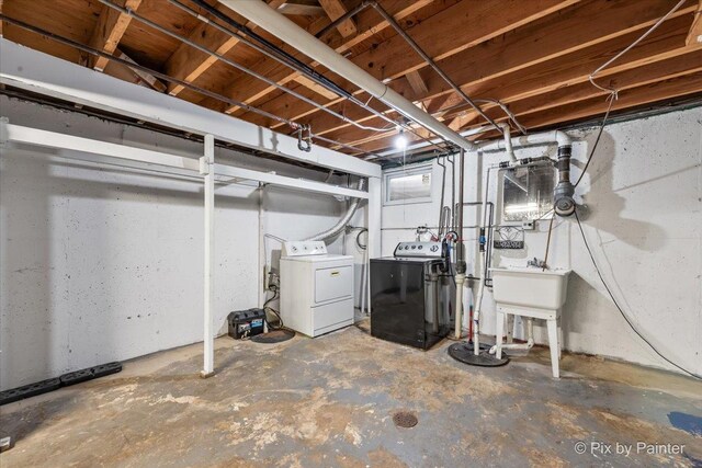 unfinished below grade area featuring washing machine and clothes dryer and a sink