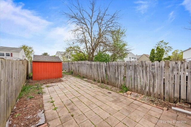 view of patio with a fenced backyard, an outbuilding, and a storage shed