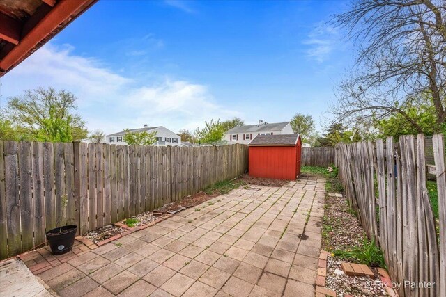 view of patio with an outbuilding, a fenced backyard, and a storage shed
