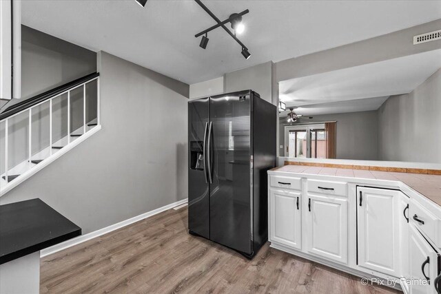 kitchen with tile counters, white cabinetry, fridge with ice dispenser, and light wood-style floors
