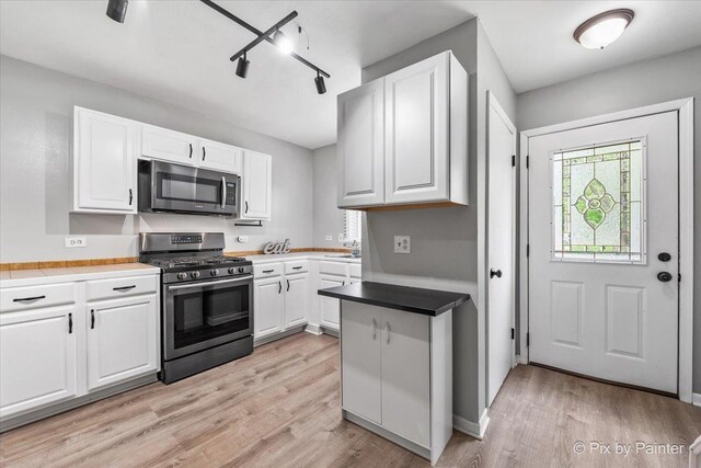 kitchen featuring light wood-style floors, appliances with stainless steel finishes, white cabinetry, and track lighting