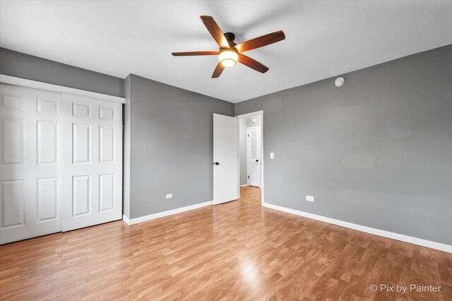 unfurnished bedroom with baseboards, a ceiling fan, light wood-style flooring, and a closet