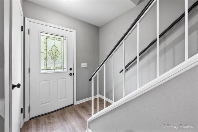 entryway with stairs, baseboards, and wood finished floors