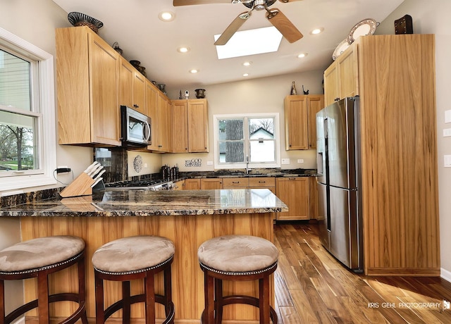 2601 N Villa Ln, Mchenry, IL 60051 - kitchen featuring appliances with stainless steel finishes, a peninsula, ceiling fan, dark wood finished floors, and a skylight