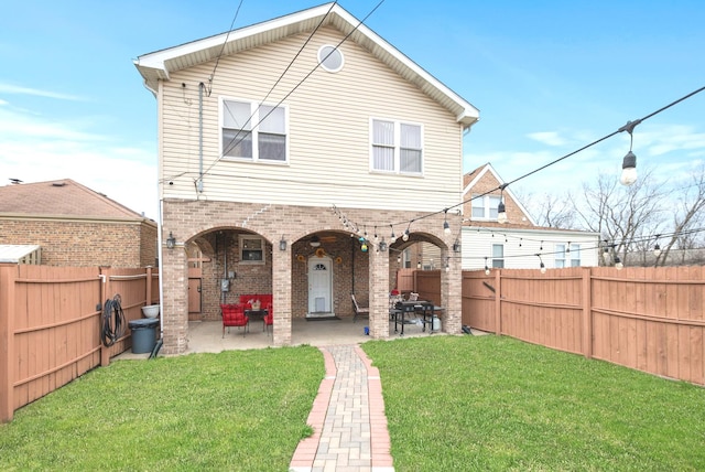 back of property with a yard, brick siding, a fenced backyard, and a patio area
