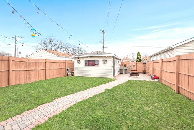 view of yard with a fenced backyard, an outbuilding, an outdoor fire pit, and a patio