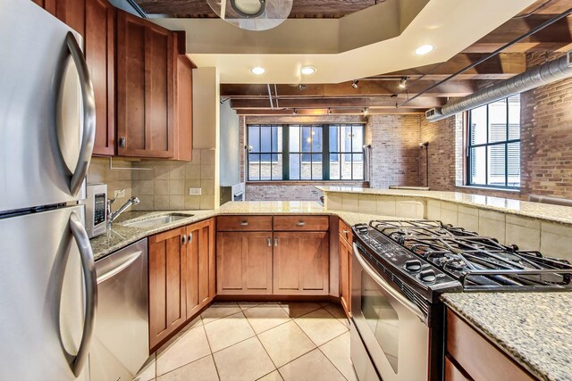 kitchen with a sink, decorative backsplash, light tile patterned floors, and stainless steel appliances
