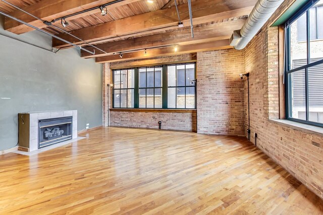 unfurnished living room featuring brick wall, wood ceiling, and wood finished floors