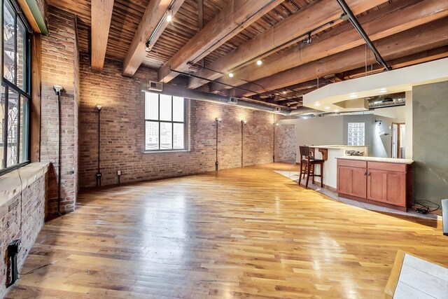 below grade area with brick wall, wooden ceiling, wood finished floors, and track lighting