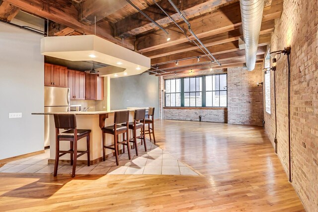 kitchen with brick wall, light countertops, freestanding refrigerator, open floor plan, and light wood-style flooring