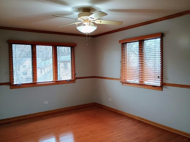 empty room with crown molding, ceiling fan, baseboards, and light wood finished floors