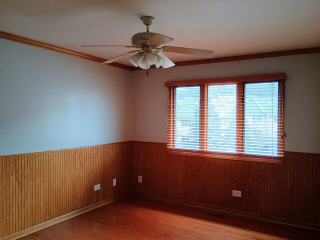 unfurnished room with wainscoting, wood finished floors, and a healthy amount of sunlight