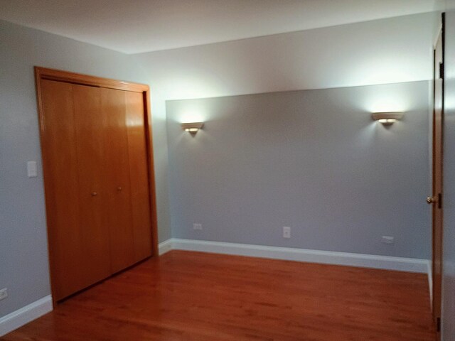 unfurnished bedroom featuring baseboards, a closet, and wood finished floors