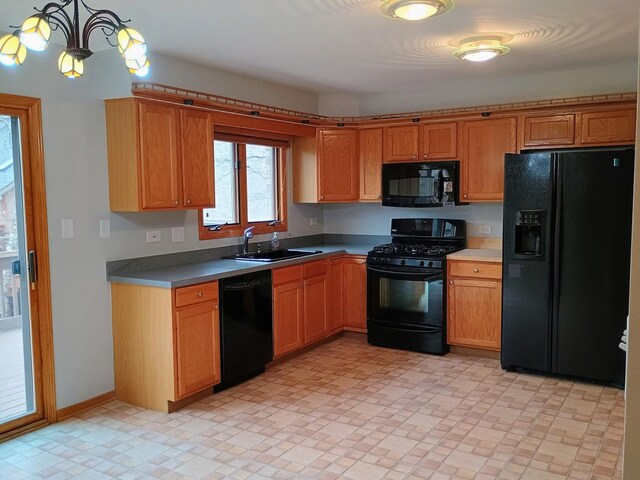 kitchen featuring decorative light fixtures, brown cabinetry, a sink, and black appliances