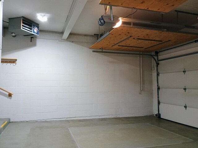 garage featuring concrete block wall, a heating unit, and a garage door opener