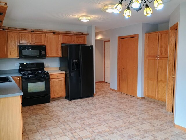 kitchen with an inviting chandelier, baseboards, light countertops, a sink, and black appliances