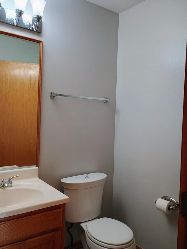 half bath featuring vanity and toilet
