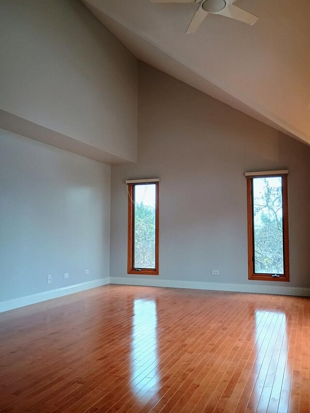 spare room featuring high vaulted ceiling, ceiling fan, baseboards, and wood finished floors