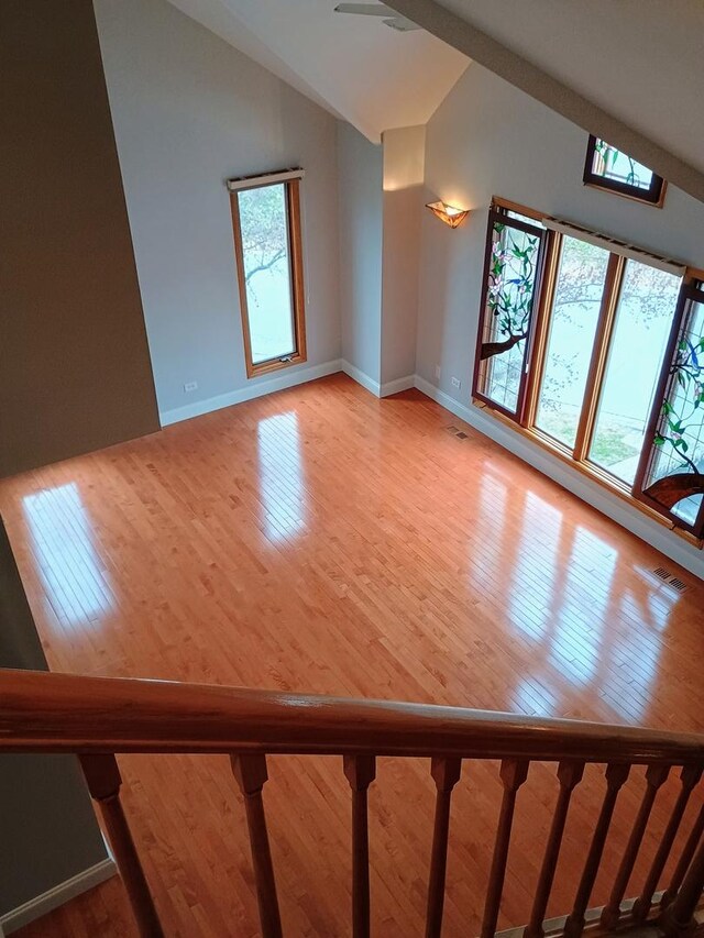 interior space with baseboards, light wood-style flooring, and high vaulted ceiling