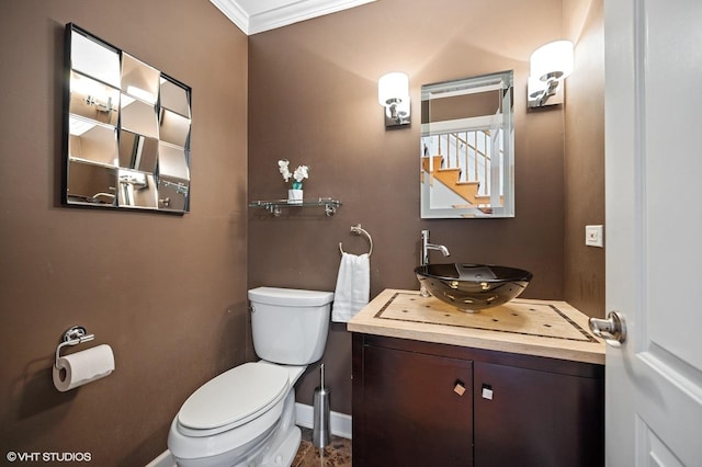 half bathroom with crown molding, toilet, baseboards, and vanity