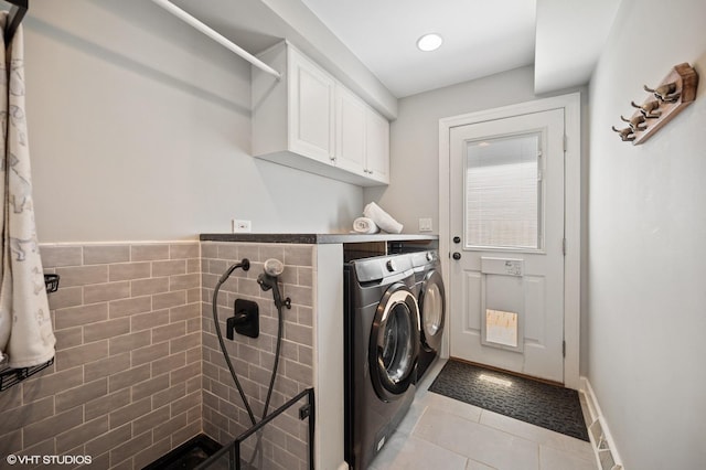 laundry area with independent washer and dryer, light tile patterned floors, and cabinet space