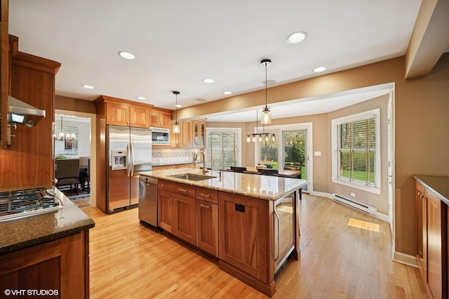 kitchen featuring brown cabinets, stainless steel appliances, a notable chandelier, and a sink