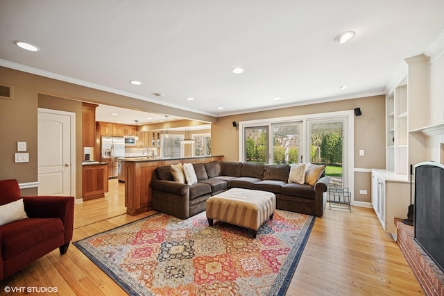 living area with crown molding, recessed lighting, and light wood-style flooring