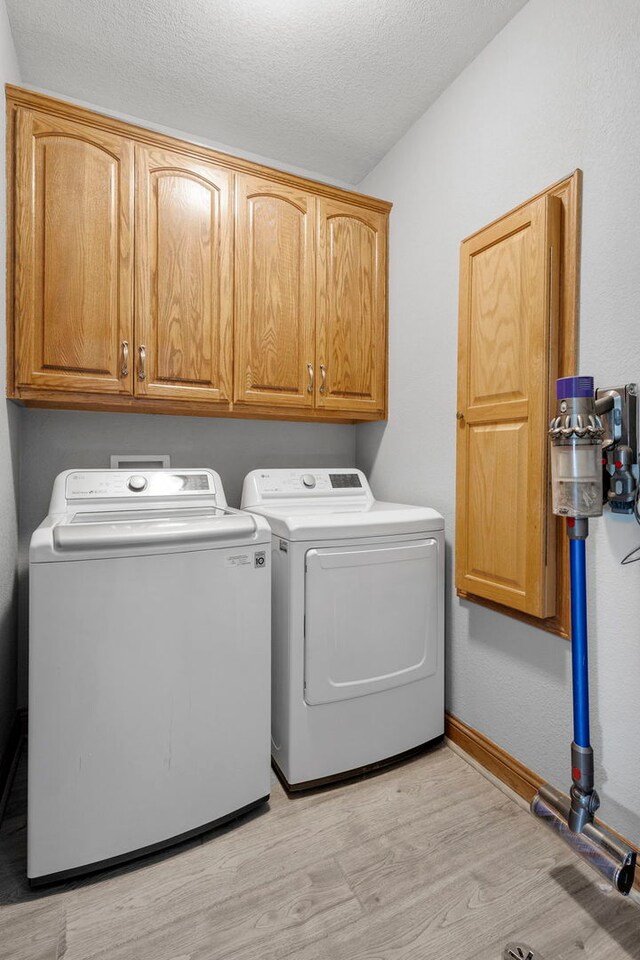 400 Rock Creek Dr, Manteno, IL 60950 - washroom featuring baseboards, a textured ceiling, cabinet space, light wood-style flooring, and independent washer and dryer
