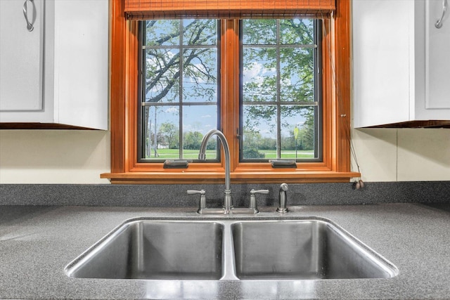 details featuring a sink, dark countertops, and white cabinetry